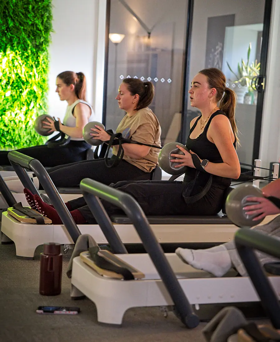 Members working with Pilates balls on the Reformers